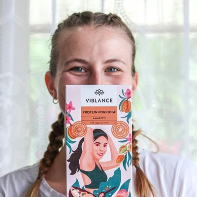 Girl showing box of Viblance Amaretti porridge